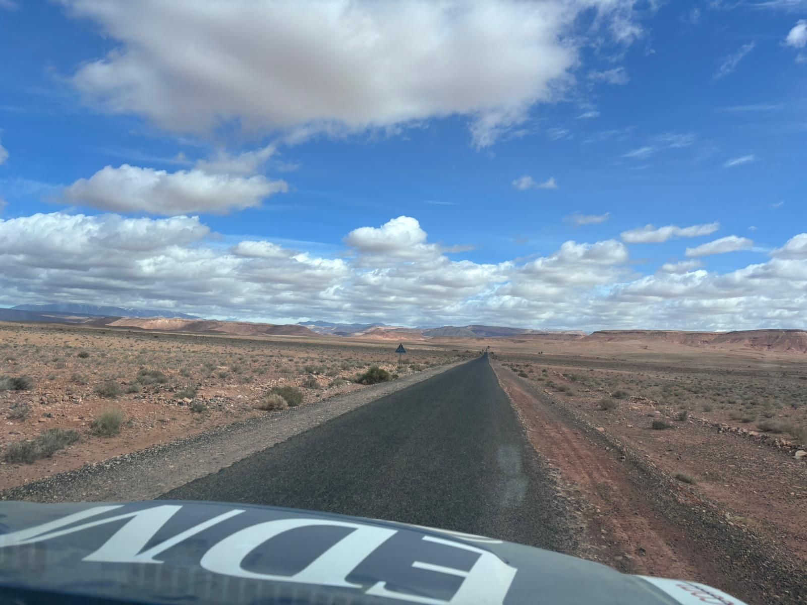 Vue depuis l'habitacle — route désertique, capot aux couleurs EDM